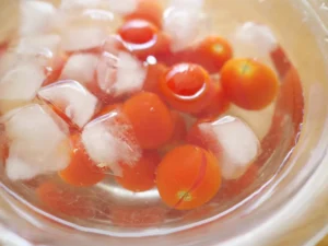 簡単レシピ　湯むきミニトマトの玉ねぎドレッシング　ライム香る冷たいサラダの作り方　ミニトマトを冷水に入れ皮をむく